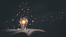 Glowing Light Bulb On A Book, Inspiring From Read Concept, Educational Knowledge And Business Education Ideas, Innovations, Self-learning, Knowledge And Searching For New Ideas. Thinking For New Idea.