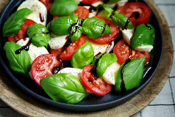 Wall Mural - Soft focus. Classic caprese salad on a dark plate. Italian recipes concept.