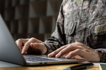 Surveillance and control of opposing information concept, Soldier in camouflage uniform working on laptop for Information Operation.