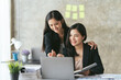 © PaeGAG - Group of young asian business people discussing something and smiling while sitting at the office table, two business people in the office working together.