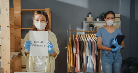 Wall Mural - Professional attractive cheerful two Asian lady owner teen with casual surgical mask hold tablet keep social distance stand together wait for customer in her shop. Reopening a Business After COVID-19.