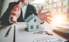 Real Estate Agents Present And Consult With Clients To Decide Whether To Sign An Insurance Contract. House Trading About Mortgage And Home Insurance Offers
