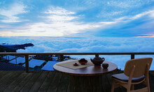 Ceramic Tea Set And Dry Tea Leave On A Wooden Table And Chair On The Balcony Or Terrace Made Of Wood. Mountain With Morning Sea Of Mist And Sunshine. Hot Tea On The Mountain Atmosphere. 3D Rendering