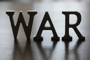 WAR, word written in wooden alphabet letters on blue background. The concept of a terrible war destroying country.