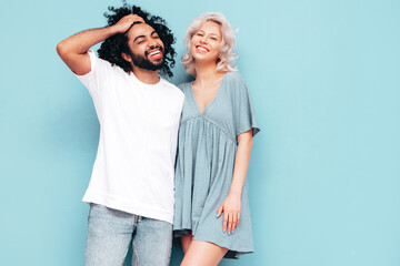 Smiling beautiful woman and her handsome boyfriend. Sexy cheerful multiracial family having tender moments on beige background in studio. Multiethnic models hugging. Embracing each other.Love concept