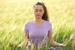 © Antonioguillem - Front view of a woman doing yoga exercise in a wheat field