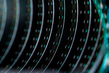 A Roll Of Twisted Retro Film Tape With Green Highlights. Twisted Analog Old Strips Of Film For A Photo Or Video Camera Close Up. The Concept Of Cinematography, Photography, Photographic Memories.