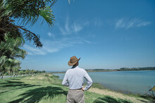 A Male Tourist And Photographer With A Cowboy Hat Stands Back In The Ecological Lakeside Park Of Maoming Open Pit Mine
