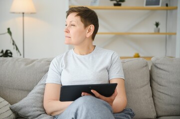 Canvas Print - people, technology and internet concept - happy middle aged woman with tablet pc computer at home.