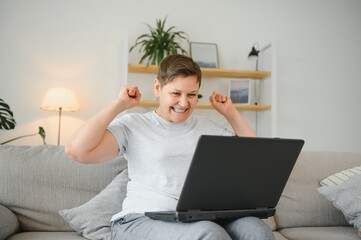 Canvas Print - Excited mature woman looking at laptop screen, reading good news in message, celebrating online lottery win, rejoicing success, overjoyed older female sitting on couch at home, using computer.