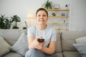 Sticker - Portrait of happy older woman changing channel on television.