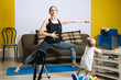 © irissca - Young mother fitness instructor personal trainer record video near camera at home with baby daughter