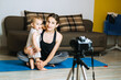 © irissca - Mom blogger records video on camera with her little daughter at home.