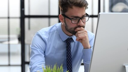 Sticker - Young man sitting at his desk in the office, working on computer.