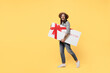 Full body happy young man he 20s wears striped grey shirt white t-shirt hat hold gift certificate coupon voucher card for store walk go isolated on plain yellow background. People lifestyle concept.