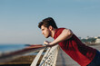 Side profile view young strong sporty toned fit sportsman man in sports clothes do push-ups exercises on railing warm up training at sunrise sun dawn over sea beach outdoor on pier seaside in morning.
