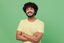 Young Smiling Confident Happy Indian Man 20s In Basic Yellow T-shirt Hold Hands Crossed Folded Look Camera Isolated On Plain Pastel Light Green Background Studio Portrait. People Lifestyle Concept