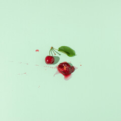 Squashed red cherry berry fruit on pastel green background. Summe red ripe juicy fruit concept.