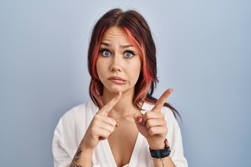 Sticker - Young caucasian woman wearing casual white shirt over isolated background pointing aside worried and nervous with both hands, concerned and surprised expression