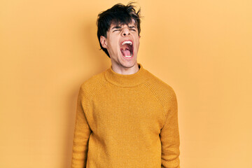 Poster - Handsome hipster young man wearing casual yellow sweater angry and mad screaming frustrated and furious, shouting with anger. rage and aggressive concept.