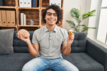 Sticker - Hispanic man with curly hair working on depression holding pills smiling and laughing hard out loud because funny crazy joke.