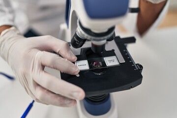 Sticker - Young hispanic man wearing scientist uniform using microscope at laboratory