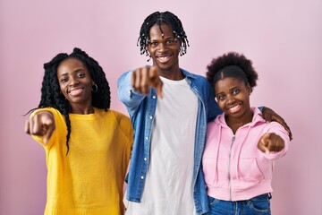 Wall Mural - Group of three young black people standing together over pink background pointing to you and the camera with fingers, smiling positive and cheerful