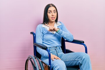 Wall Mural - Beautiful woman with blue eyes sitting on wheelchair pointing aside worried and nervous with forefinger, concerned and surprised expression