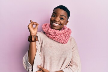 Poster - Young african american woman wearing winter scarf smiling happy pointing with hand and finger to the side