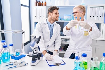 Sticker - Mother and son scientist partners holding test tubes writing on clipboard at laboratory