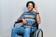 © Krakenimages.com - Handsome hispanic man sitting on wheelchair smiling positive doing ok sign with hand and fingers. successful expression.