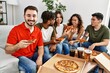 © Krakenimages.com - Group of young friends smiling happy eating italian pizza sitting on the sofa at home.
