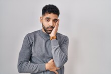 Hispanic Man With Beard Standing Over White Background Thinking Looking Tired And Bored With Depression Problems With Crossed Arms.