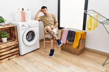 Wall Mural - Young hispanic man waiting for washing machine at laundry room