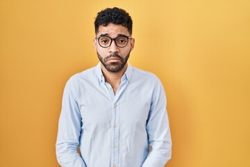 Wall Mural - Hispanic man with beard standing over yellow background depressed and worry for distress, crying angry and afraid. sad expression.