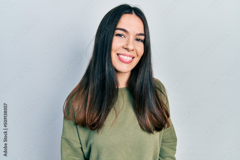 Young brunette woman wearing casual green sweater looking positive and happy standing and smiling with a confident smile showing teeth