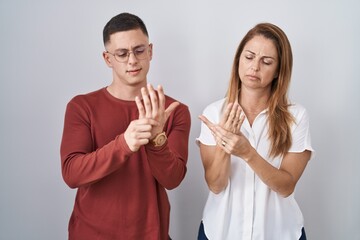 Sticker - Mother and son standing together over isolated background suffering pain on hands and fingers, arthritis inflammation