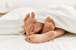 © Krakenimages.com - Couple feet under sheets on the bed at home.