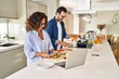 © Krakenimages.com - Middle age hispanic couple cooking and using laptop at kitchen