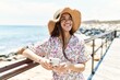 © Krakenimages.com - Young latin girl wearing summer hat using smartphone at the beach.