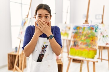 Canvas Print - Young brunette woman at art studio shocked covering mouth with hands for mistake. secret concept.