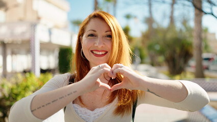 Poster - Young redhead woman smiling confident doing heart gesture with hands at park