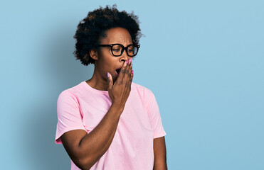 Wall Mural - African american woman with afro hair wearing casual clothes and glasses bored yawning tired covering mouth with hand. restless and sleepiness.