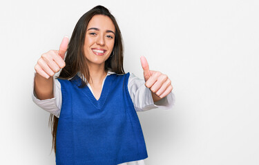 Young hispanic girl wearing casual clothes approving doing positive gesture with hand, thumbs up smiling and happy for success. winner gesture.