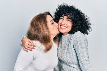 Wall Mural - Young brunette woman and senior woman standing over isolated background. Daughter and mother hugging and bonding together as happy family