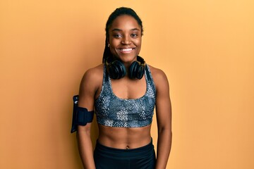 Wall Mural - African american woman with braided hair wearing sportswear and arm band with a happy and cool smile on face. lucky person.