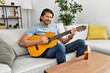© Krakenimages.com - Middle age caucasian man smiling confident playing classical guitar at home