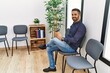 © Krakenimages.com - Young hispanic man drinking coffee sitting on chair at waiting room