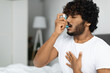 © Prostock-studio - Indian guy suffering from asthma, using inhaler in bed