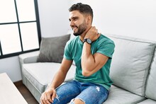 Young Arab Man Suffering For Neck Pain Sitting On Sofa At Home